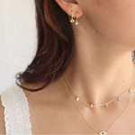 Portrait of a woman in a white blouse accessorized with the Evie Hoops 14K Gold Plated earrings