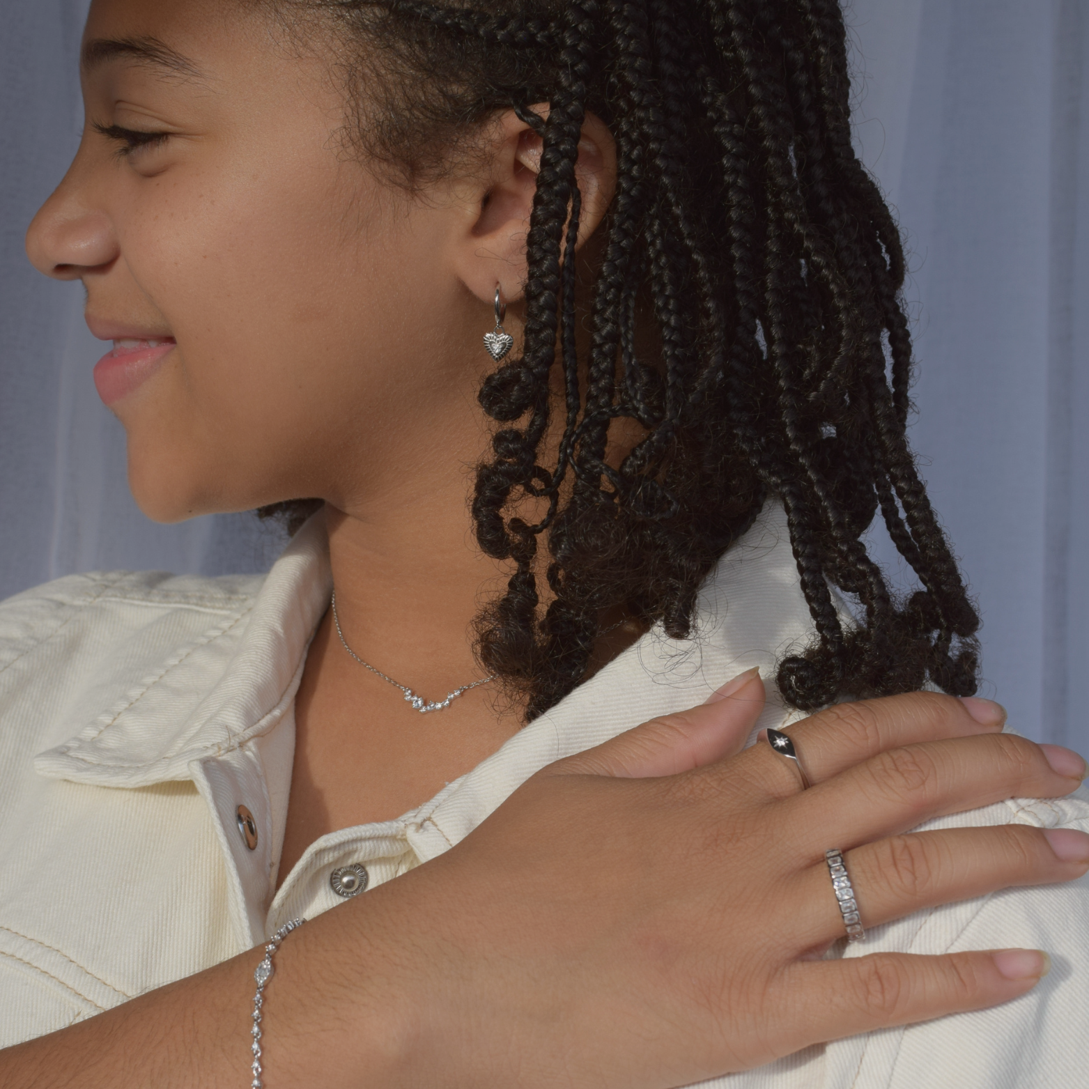 Sterling silver heart hoop earrings modeled by a person with braided hair